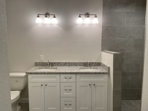 Modern bathroom vanity with dual sinks and bright lighting.