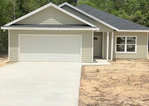 Newly built single-story house with a clean driveway and beige siding.