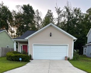 Small beige house with a two-car garage and red front door.