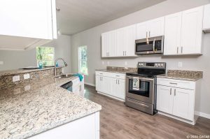 Modern kitchen with white cabinets and granite countertops.