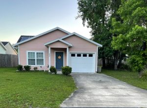 A neat pink house with a blue door and attached garage.