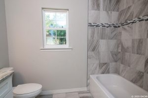 Modern bathroom with white tub, toilet, and marble-patterned wall tiles.