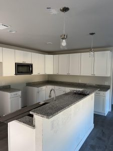 Modern kitchen with white cabinets and granite countertops.