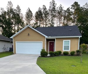 A single-story yellow house with a two-car garage and a red front door.