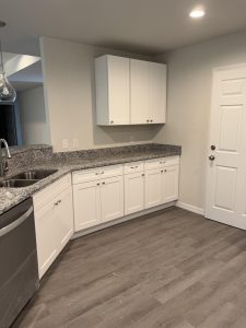 Modern kitchen with white cabinets and gray countertops.